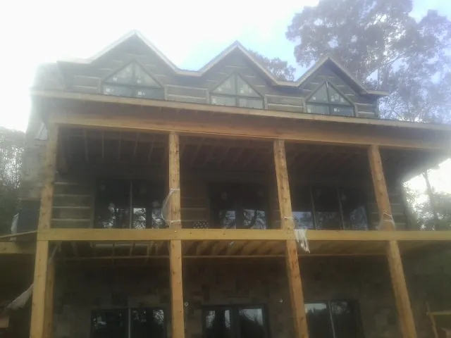 Dormers and porch framing on a large log home under construction — Roof Coating work by our crew in Hemingway