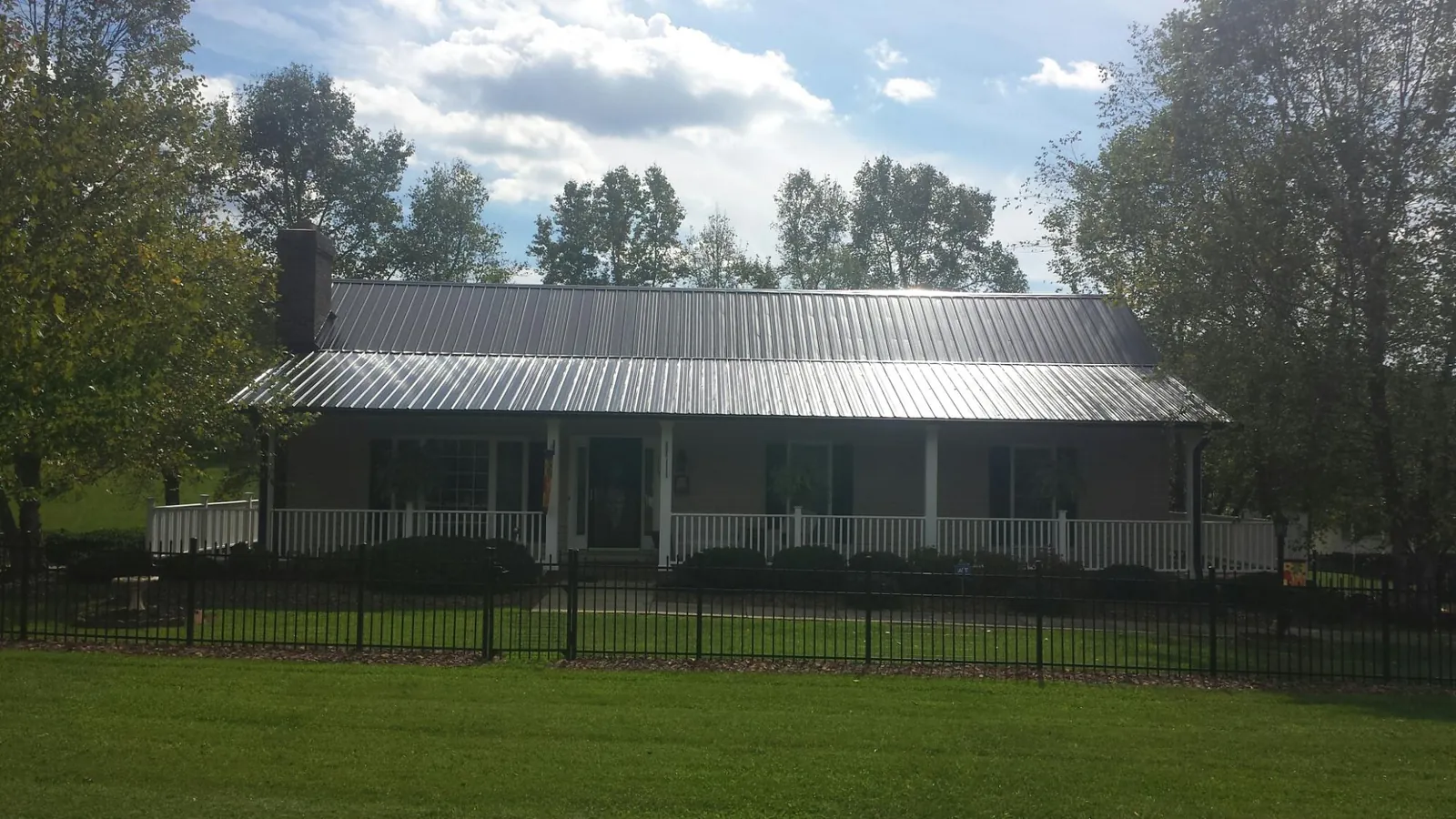 Gray metal roof on a brick ranch with a full width front porch — Gutter Guard Installation work by our crew in Hemingway