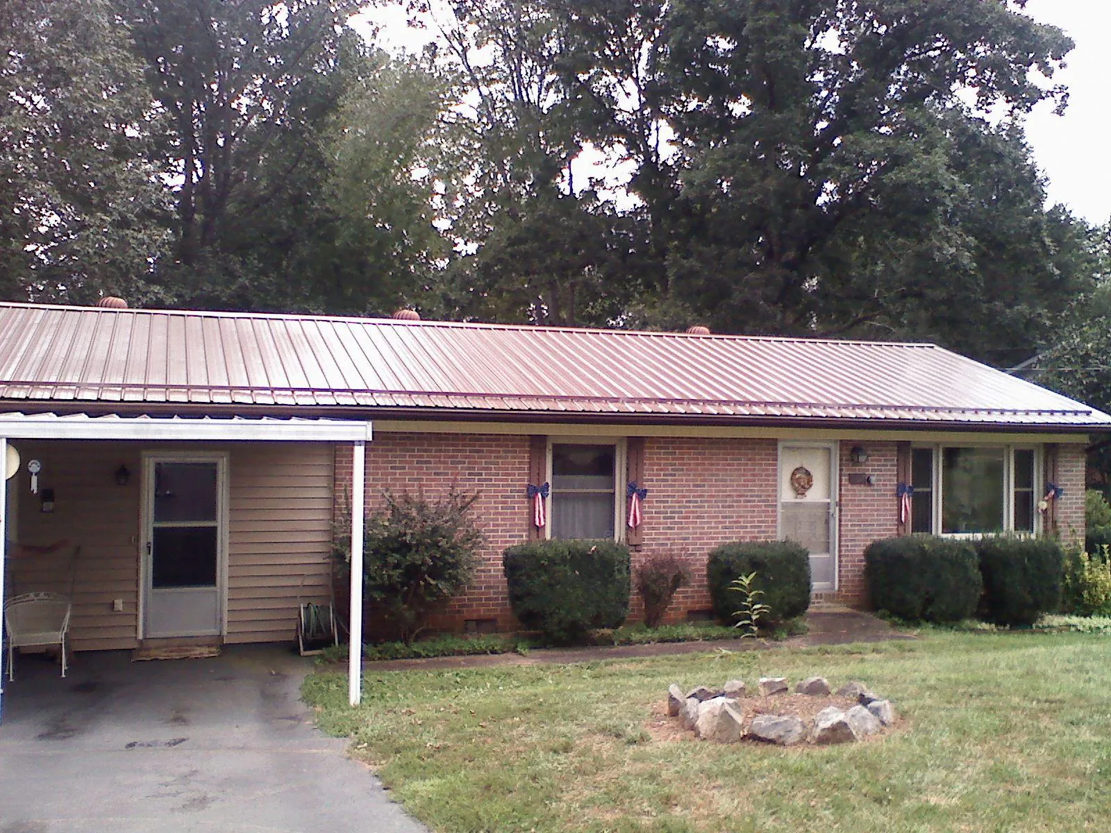 Bronze metal roof and carport on a brick ranch home — Roof Repair work by our crew in Hemingway
