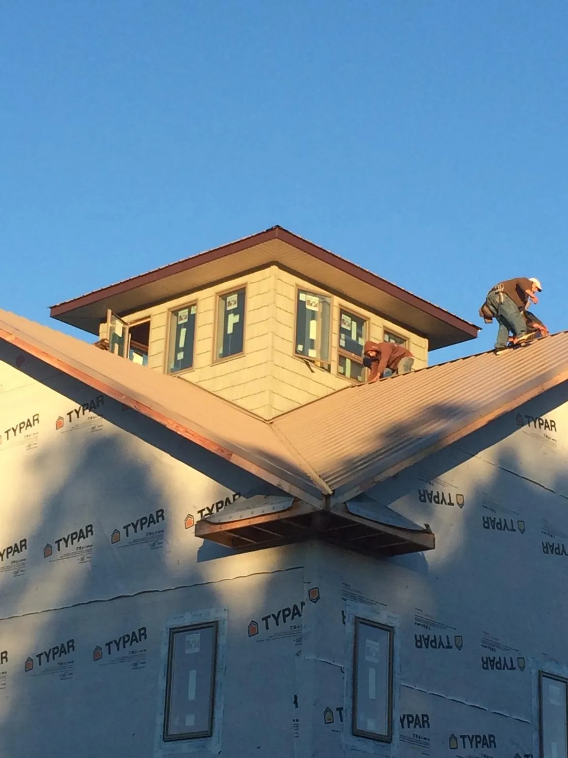 Roofers working around a rooftop cupola on a new metal roof at sunset — Roof Waterproofing in Hemingway by Roofing Brothers